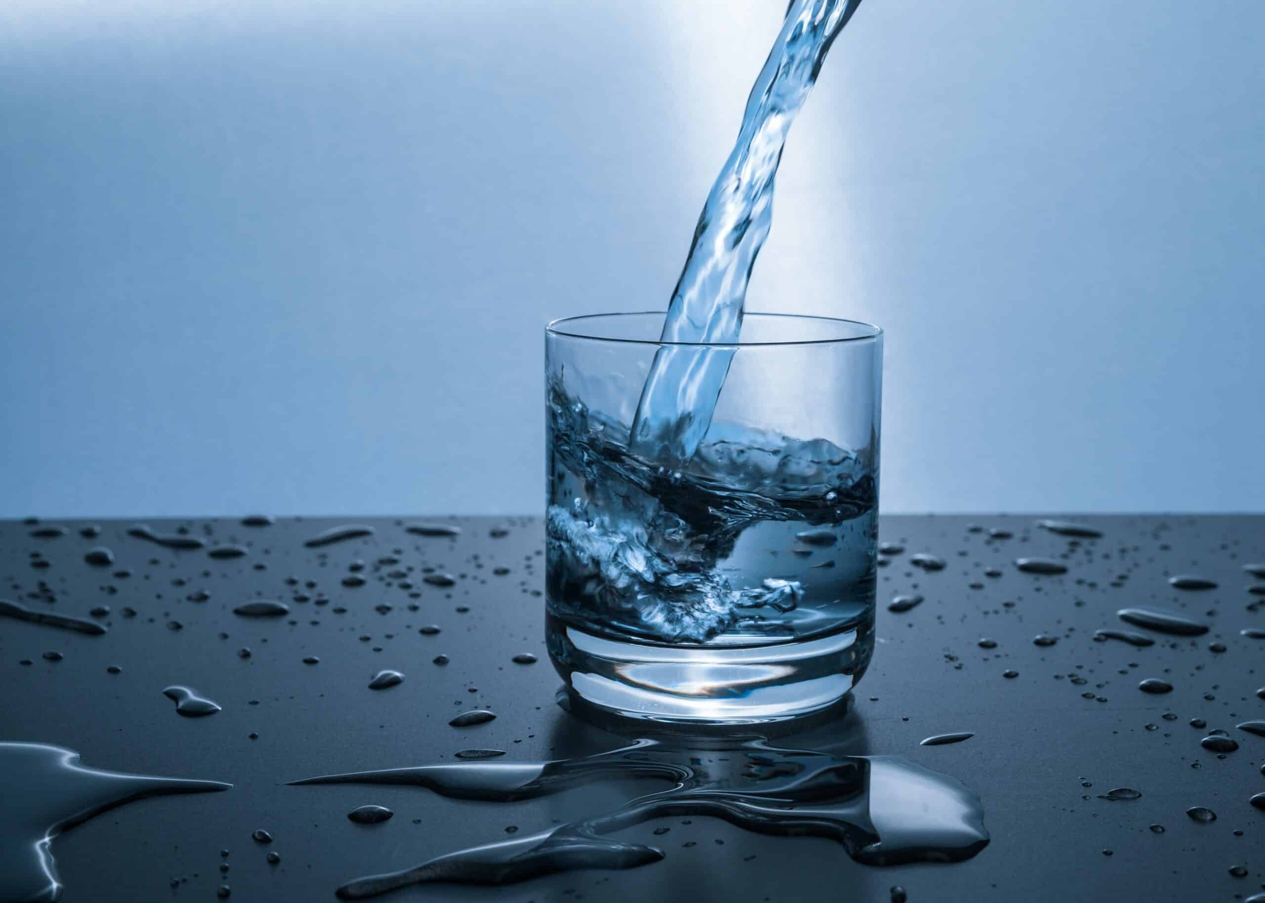 water being poured into a glass on a wet surface
