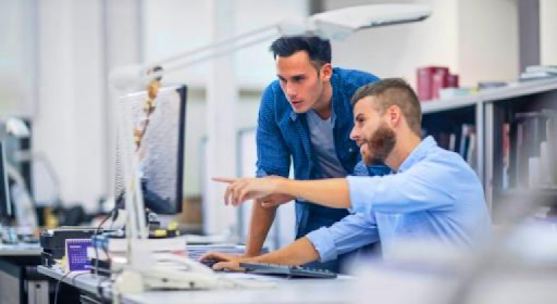 man sitting pointing to and a showing a computer screen to man standing next to him